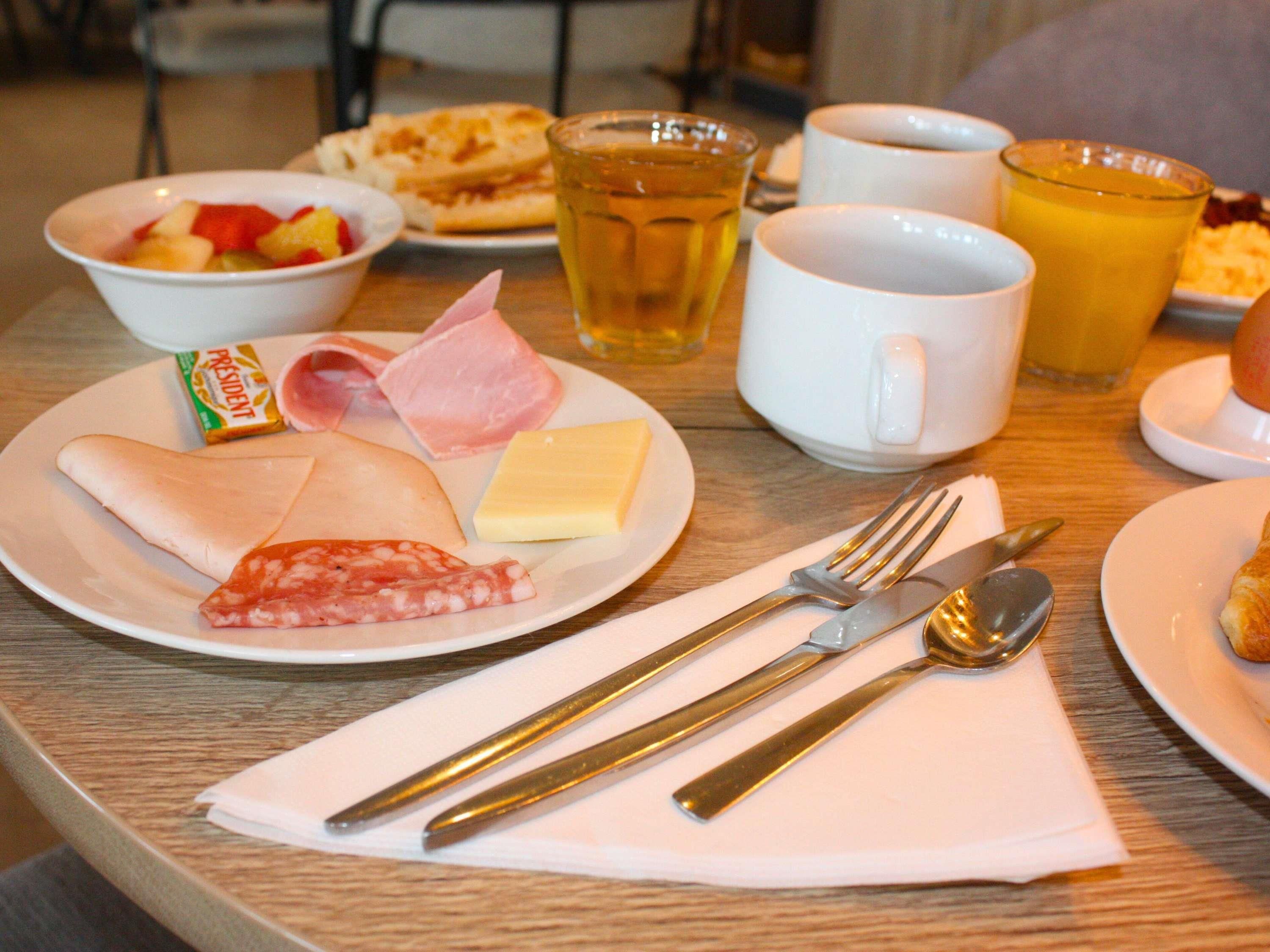 A breakfast setting with plates of food, a cup of tea, and a glass of juice.