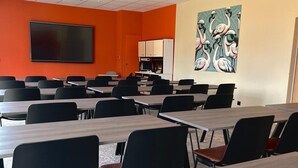 A conference room with multiple tables and chairs, a large screen, and a painting of flamingos on the wall. - Aparthotel Adagio Access Porte De Camargue (Saint-Martin-de-Crau)