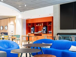 Un intérieur moderne avec des espaces salon, des tables et un bar équipé d’un écran.