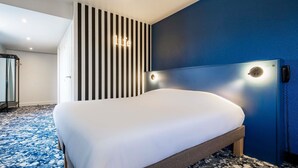 Een hotelkamer met een bed, een gestreepte wand, een blauwe accentmuur en een kamerbreed tapijt met dessin.