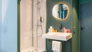 A modern bathroom with a glass-enclosed shower, a white sink, and a mirror with a round frame.