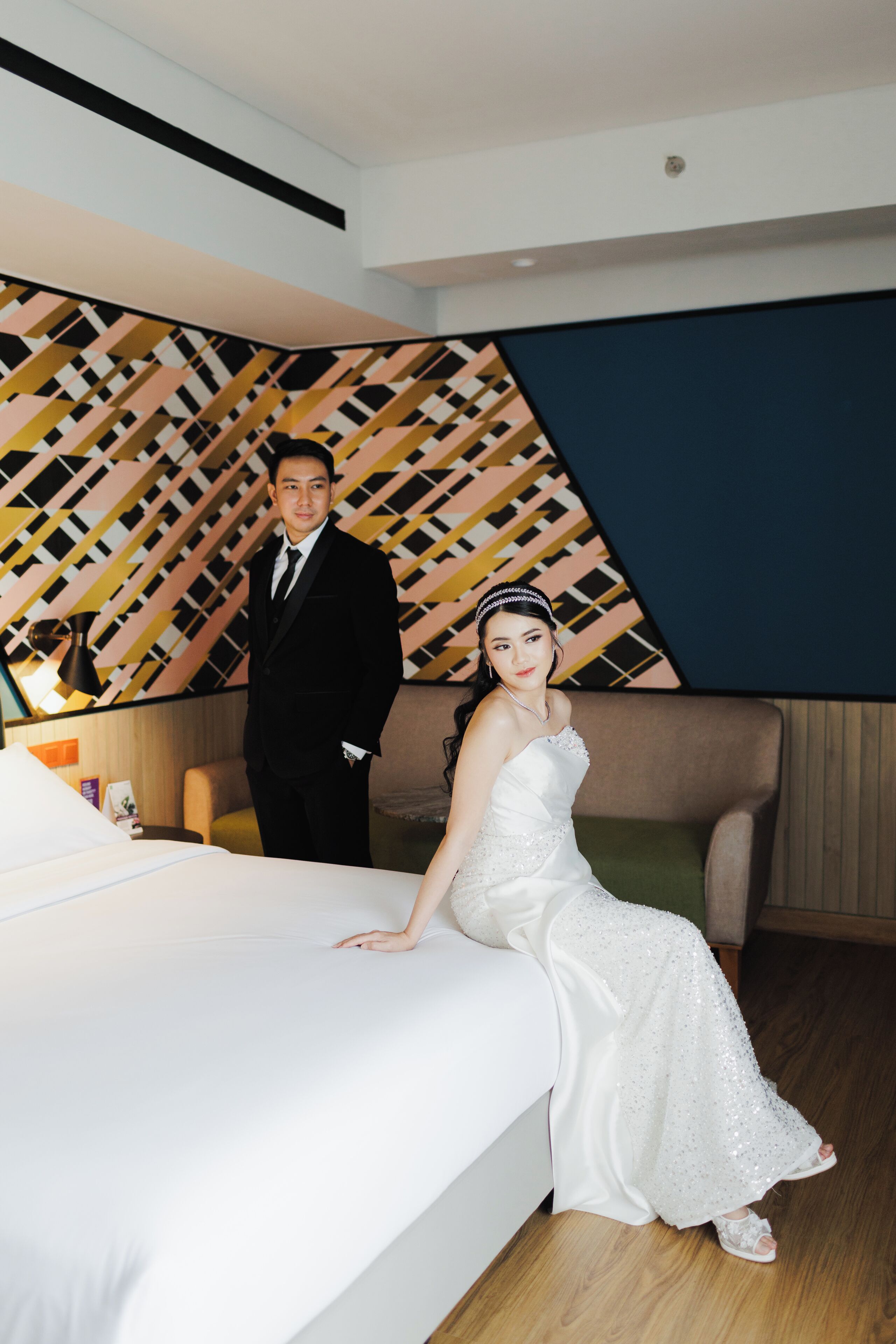 A hotel room with a bed, a sofa, and a patterned wall.