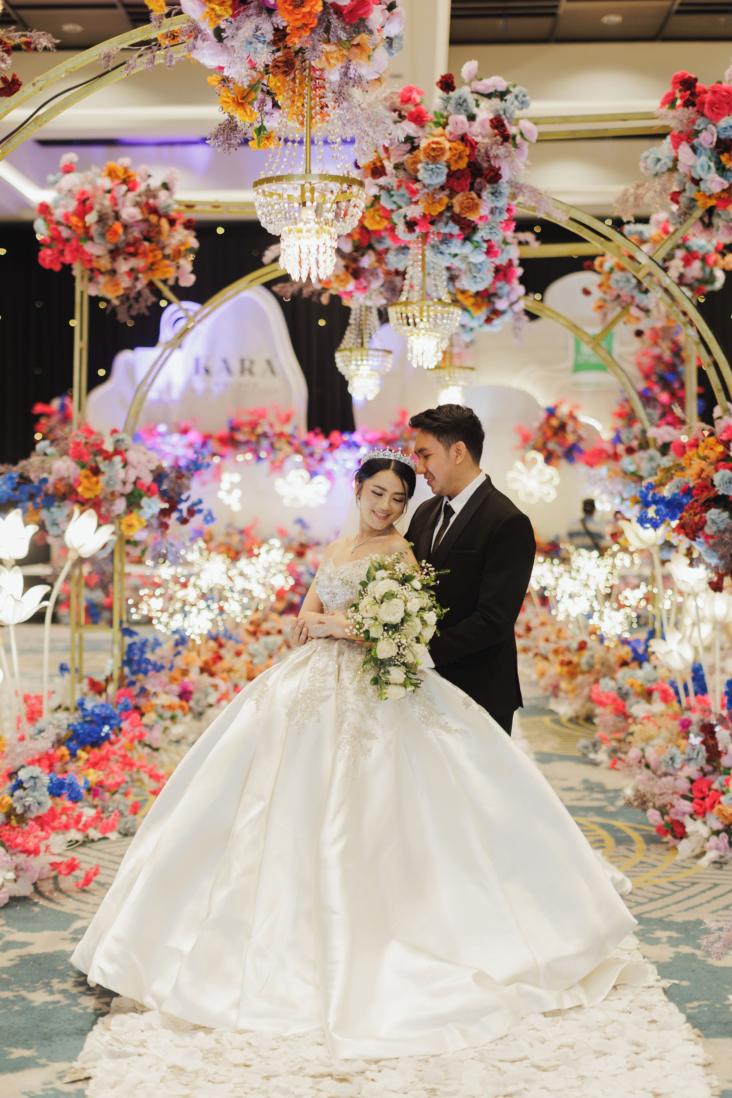 A wedding scene with a couple under a floral arch.