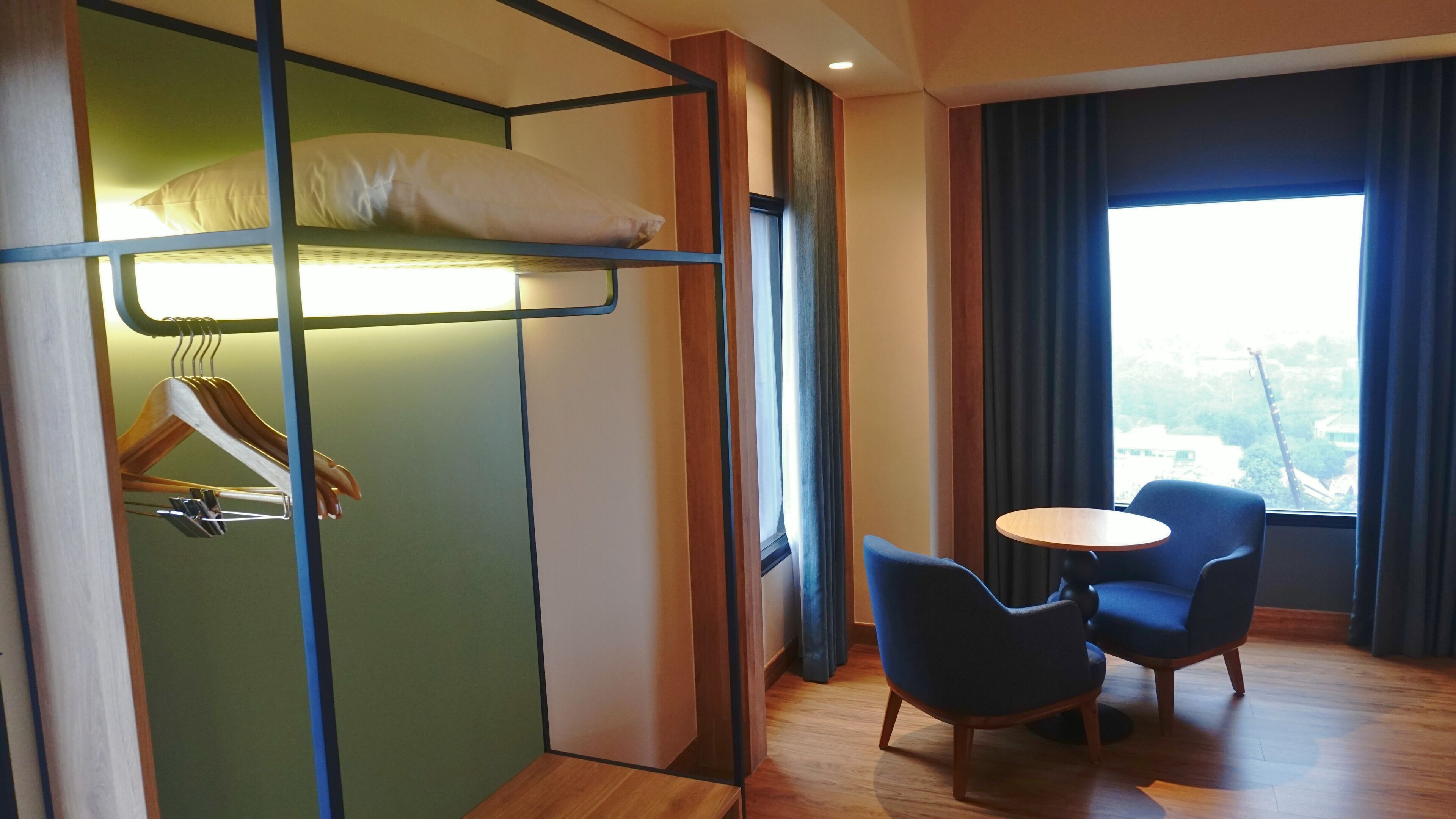 Une chambre d’hôtel avec un lit superposé, une table en bois, deux chaises et une vue sur l’extérieur.