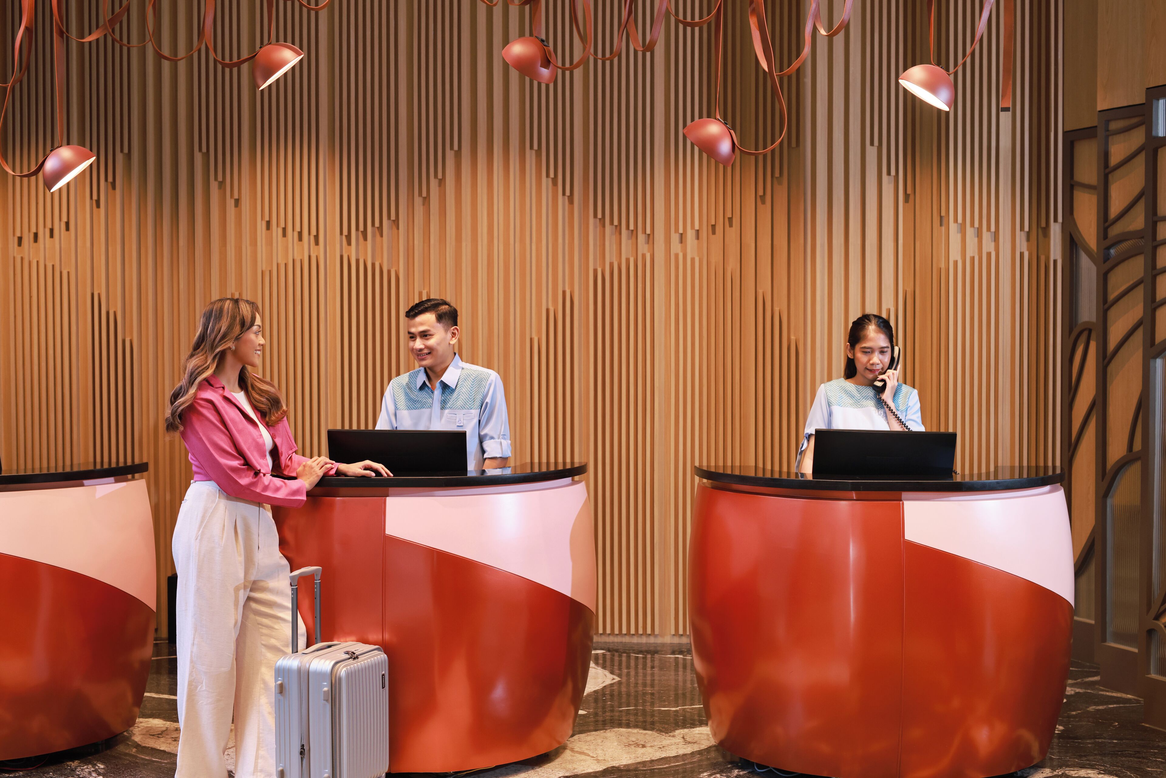 Een receptiezone met drie balies, een wand met verticale lamellen en een trap op de achtergrond.