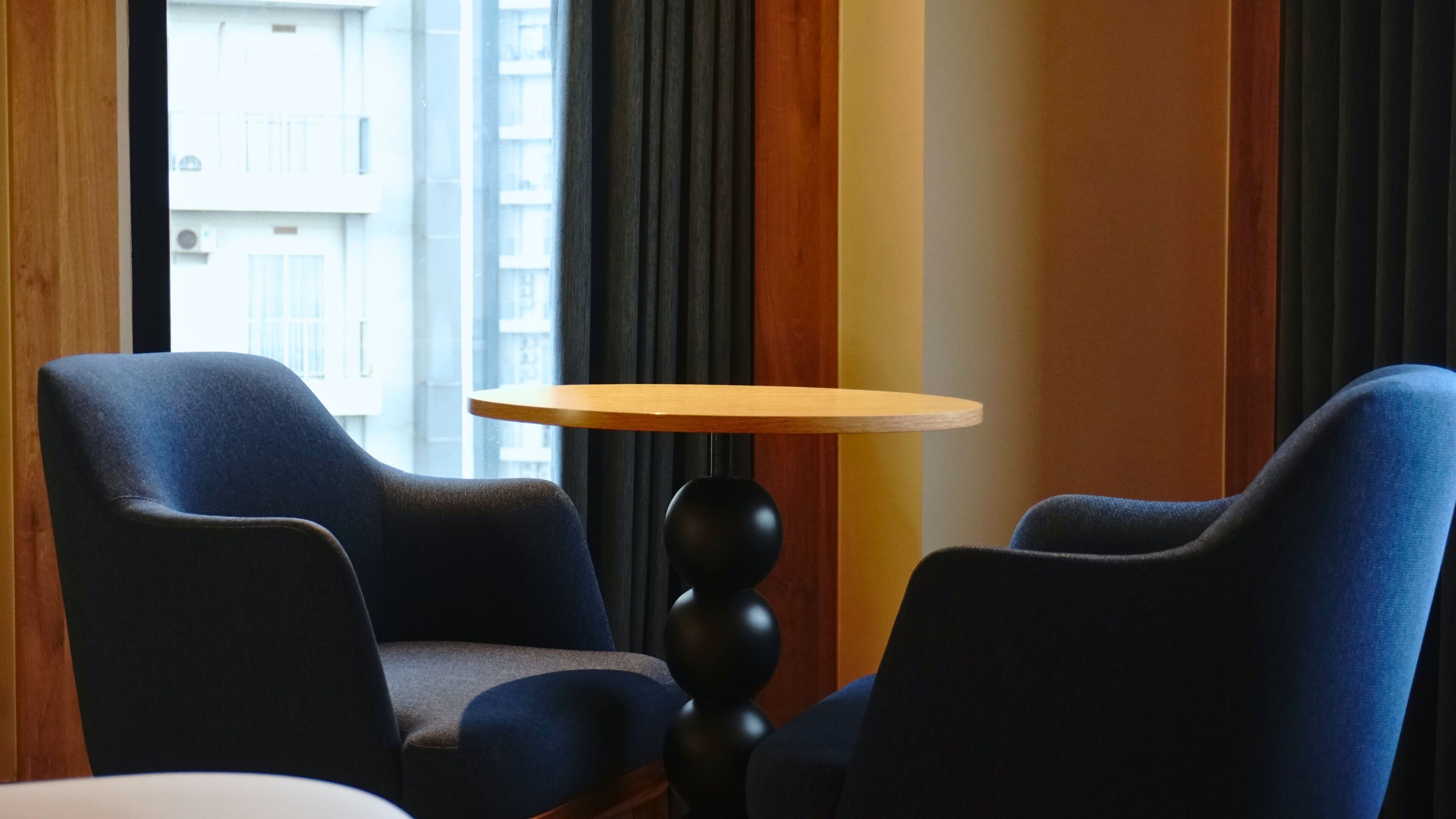 A room with two blue armchairs, a small wooden table, and a black floor lamp.
