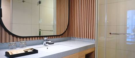 A modern bathroom with a large mirror, a sink, and a wooden panel wall.