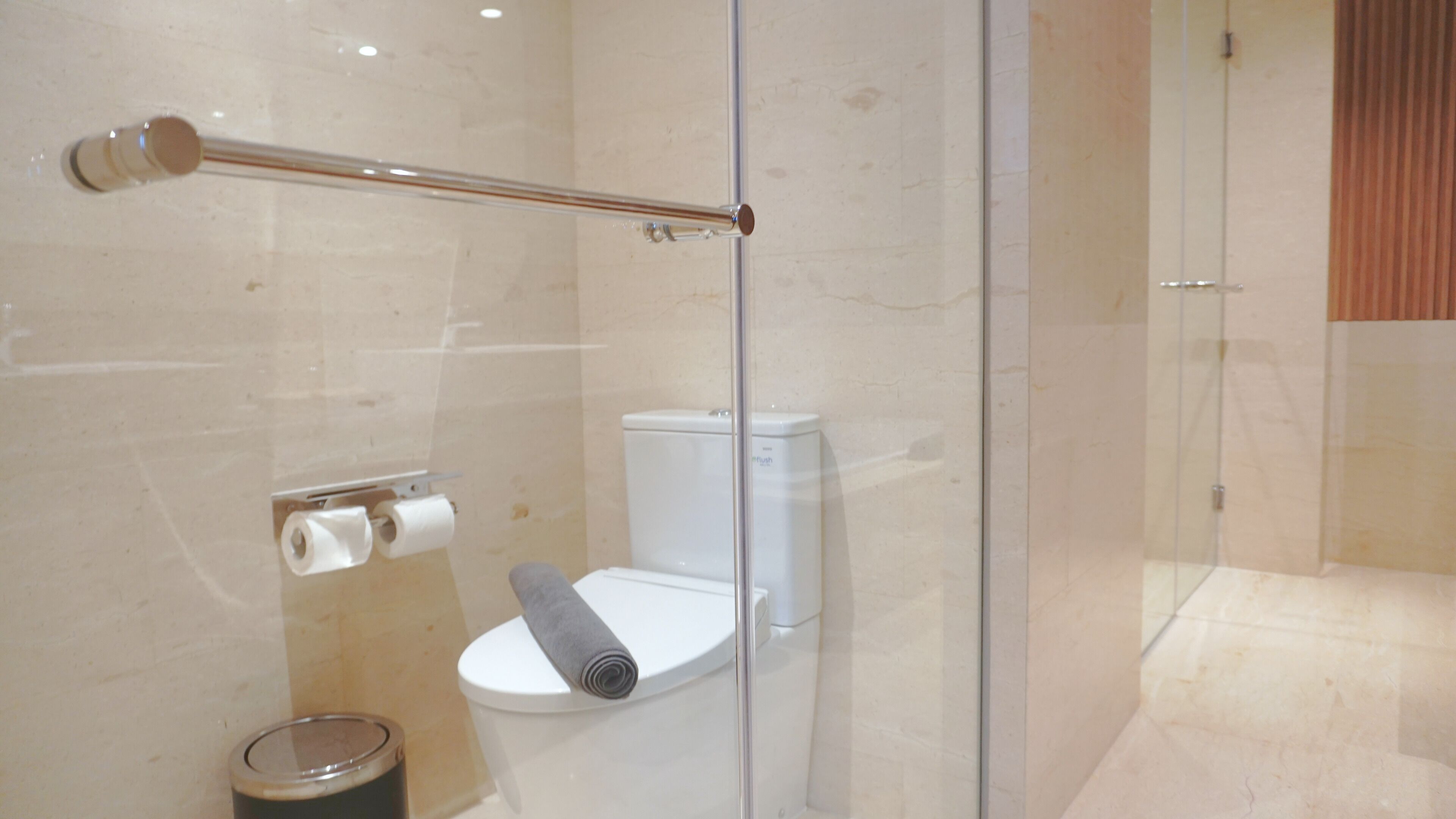 A modern bathroom with a glass shower enclosure, a toilet, and a toilet paper holder.
