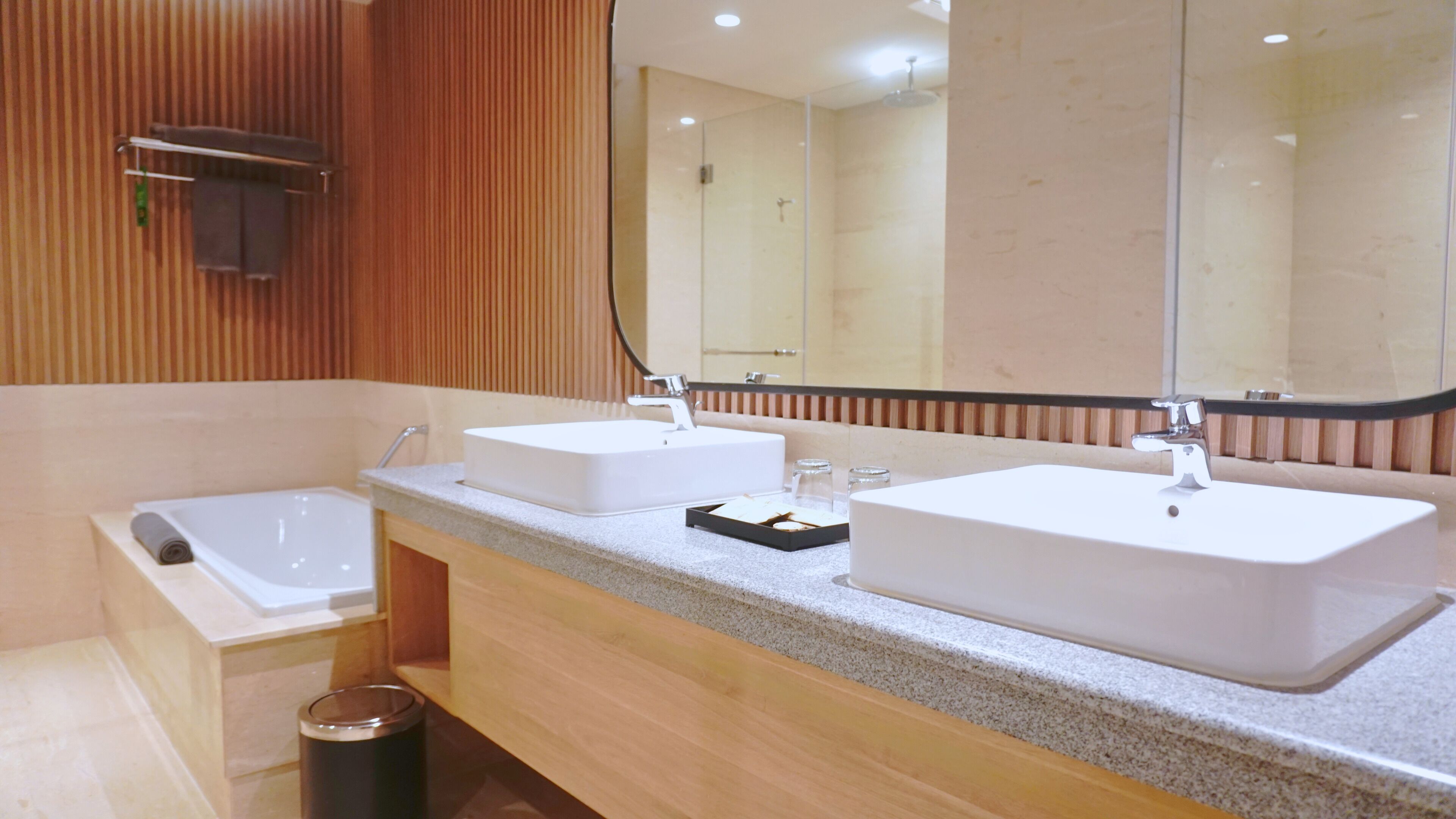 Un baño moderno con dos lavamanos, un espejo grande y una ducha.