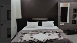 Una habitación de hotel moderna con una cama grande, una mesita de noche, un espejo y un armario.