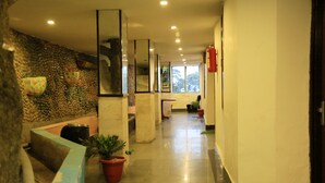 Un vestíbulo de hotel con pared de piedra, una recepción y un extintor.