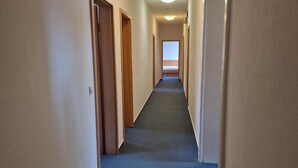 A long, narrow hallway with carpeted floors and wooden doors on both sides. - Stadthotel im Kolpinghaus  (Werne)
