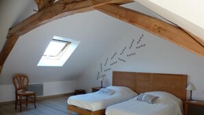 A bedroom with two beds, a skylight, and a wooden ceiling structure.