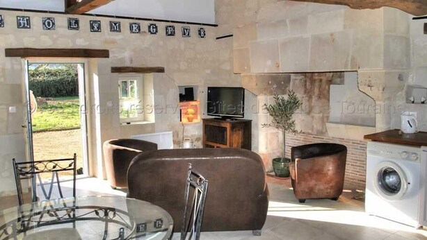 A spacious living area with a stone fireplace, a television, and a washing machine.