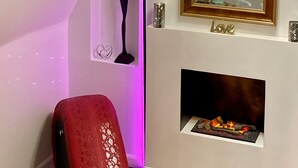 Ein Zimmer mit Kamin, Spiegel und einem roten Sessel.