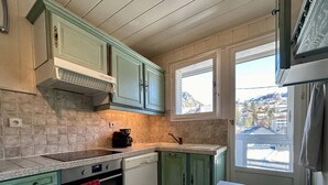 A kitchen with teal cabinets, a built-in oven, and a window with a view of a mountain.