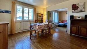 A cozy room with a wooden dining table, chairs, a sofa, and a bookshelf.