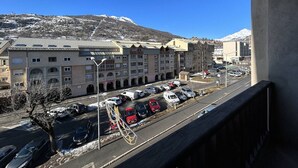 A hotel with multiple floors, a parking lot with several cars, and a mountainous backdrop.
