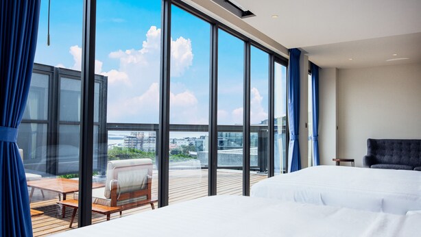 A modern hotel room with a large balcony, a bed, a sofa, and a small table. - HOTEL BEGINS (Keelung)