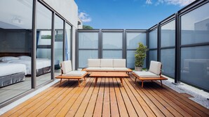 A modern outdoor living space with a wooden deck, a sofa set, and a potted plant. - HOTEL BEGINS (Keelung)