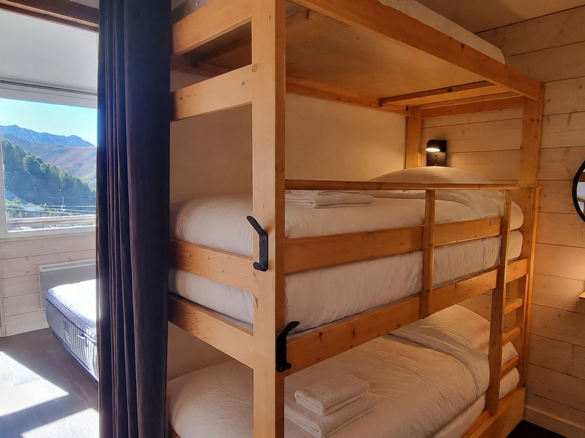 A bunk bed with a view of mountains through a window.