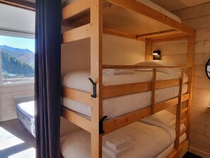 A bunk bed with a view of mountains through a window.