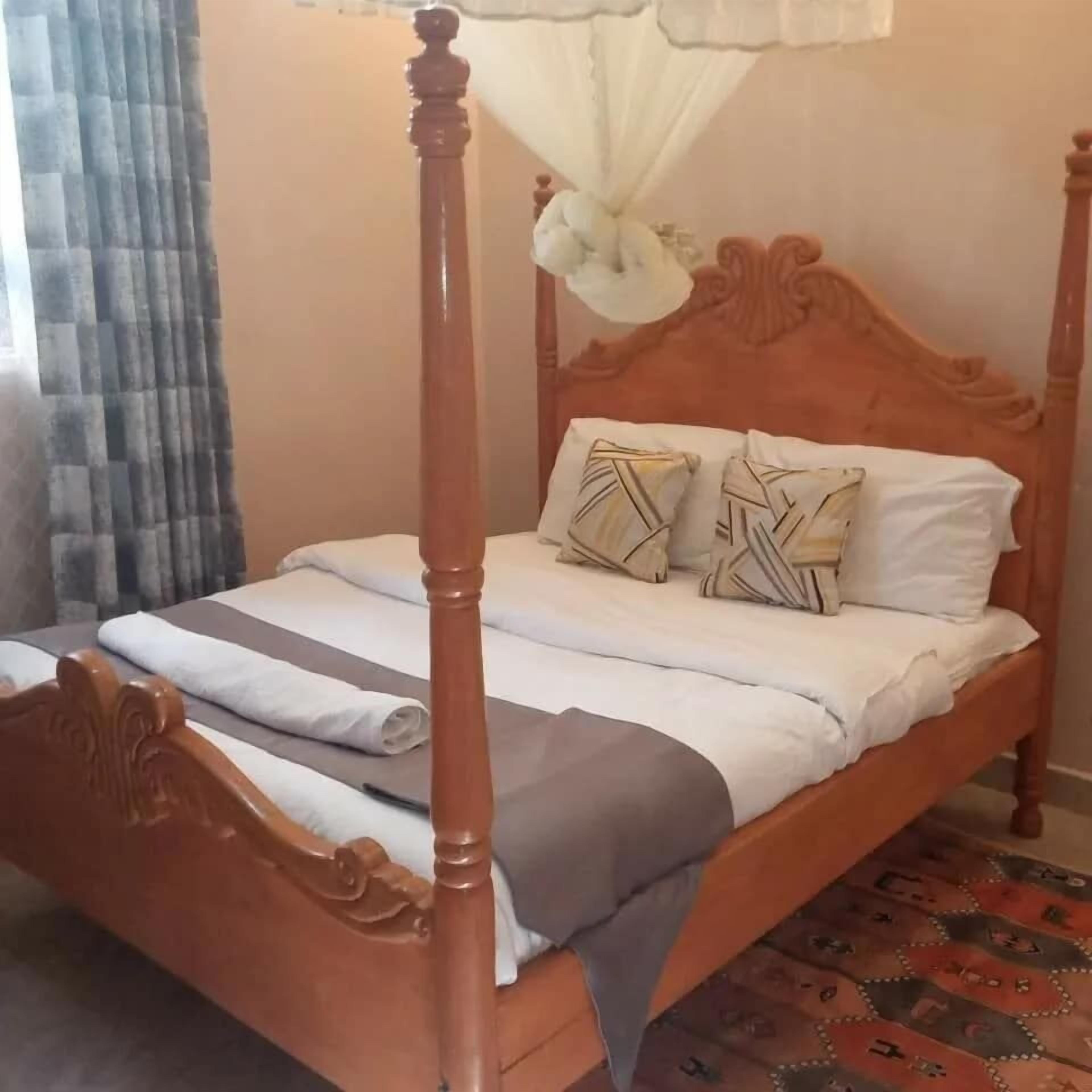 Un lit à baldaquin, deux oreillers à motifs géométriques et une couverture à rayures.