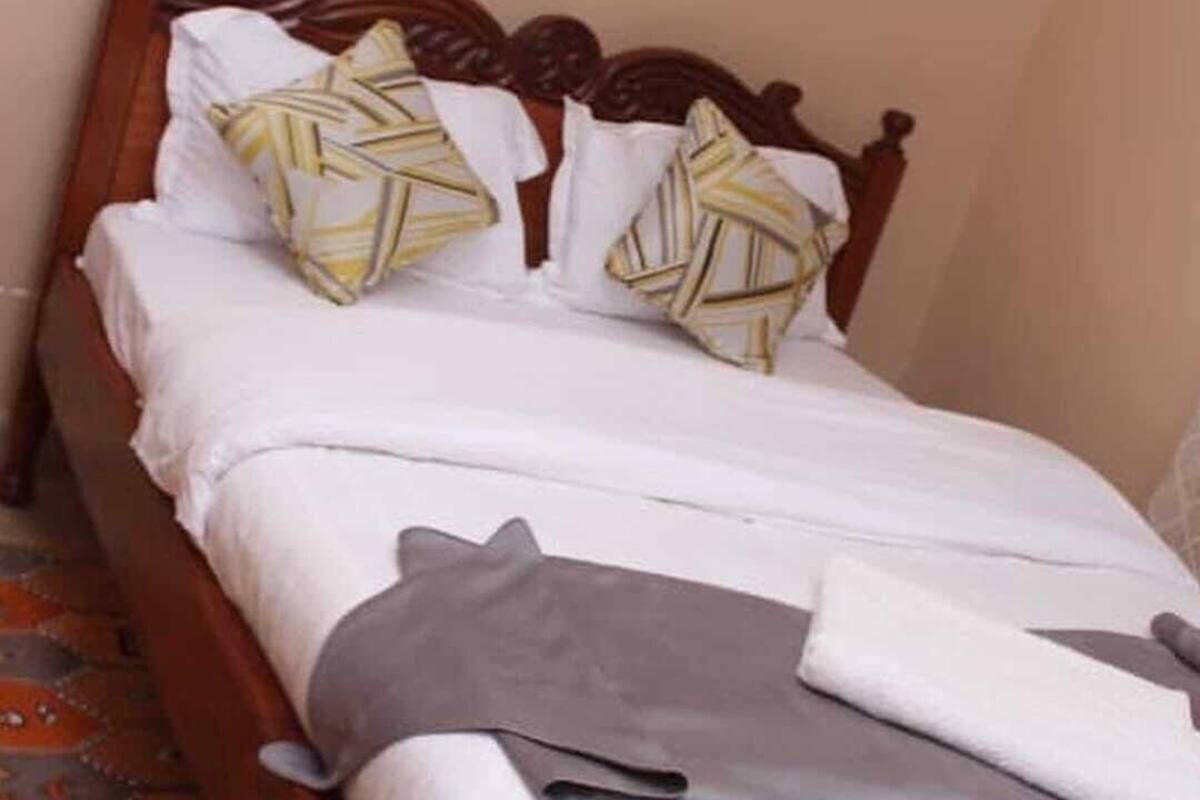 A bed with a wooden headboard, white bedding, and patterned pillows.