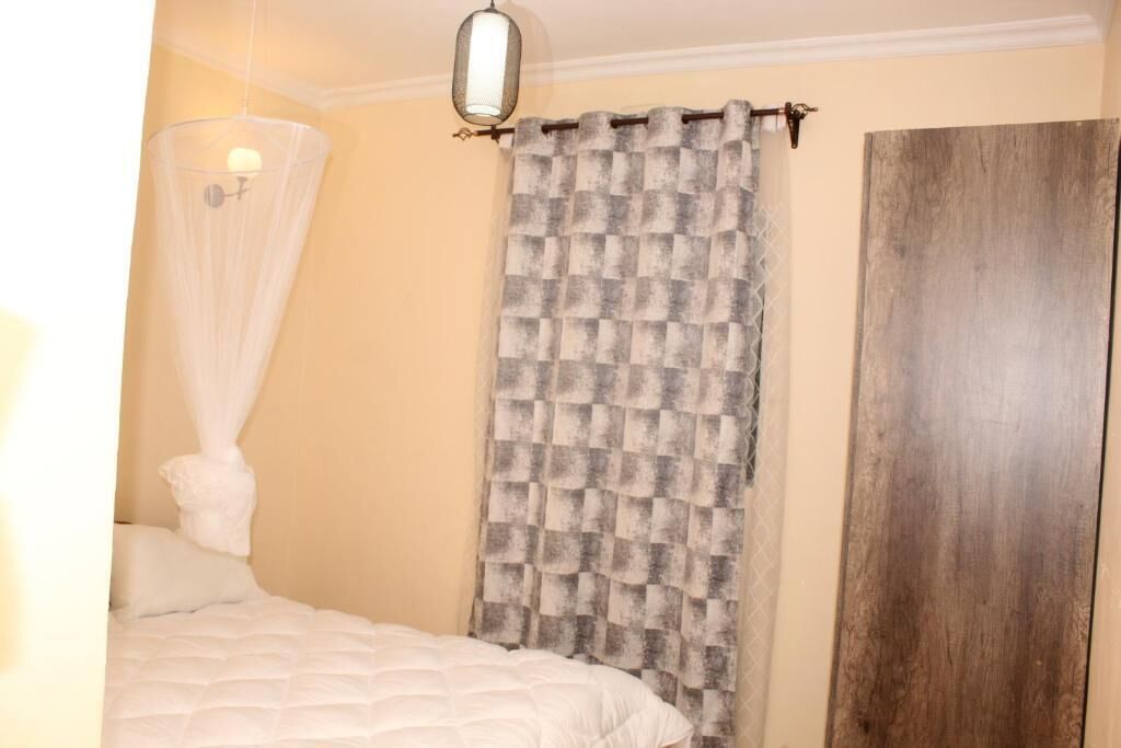 Quarto com cama, dossel, cortina xadrez e porta de madeira.