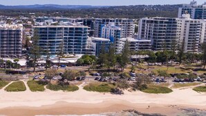 A coastal cityscape with high-rise buildings, a sandy beach, and a parking area. - Zanzibar 505 amazing beachfront resort apartment withm pool , spa and access to gym (Mooloolaba)