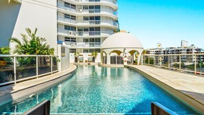 A swimming pool with a clear blue water, surrounded by a white building with balconies and a dome structure. - Zanzibar 505 amazing beachfront resort apartment withm pool , spa and access to gym (Mooloolaba)