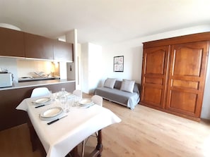 Un comedor con una mesa preparada para cuatro personas, un sofá y un armario de madera.