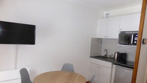 A compact kitchen with a microwave, sink, and a small refrigerator. There is a round wooden table with four chairs. A flat-screen TV is mounted on the wall. - Studio for 4 at Hameaux du Lay with parking (Les Contamines-Montjoie)
