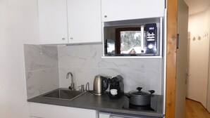 A compact kitchen with a sink, a coffee maker, and a stove. - Studio for 4 at Hameaux du Lay with parking (Les Contamines-Montjoie)