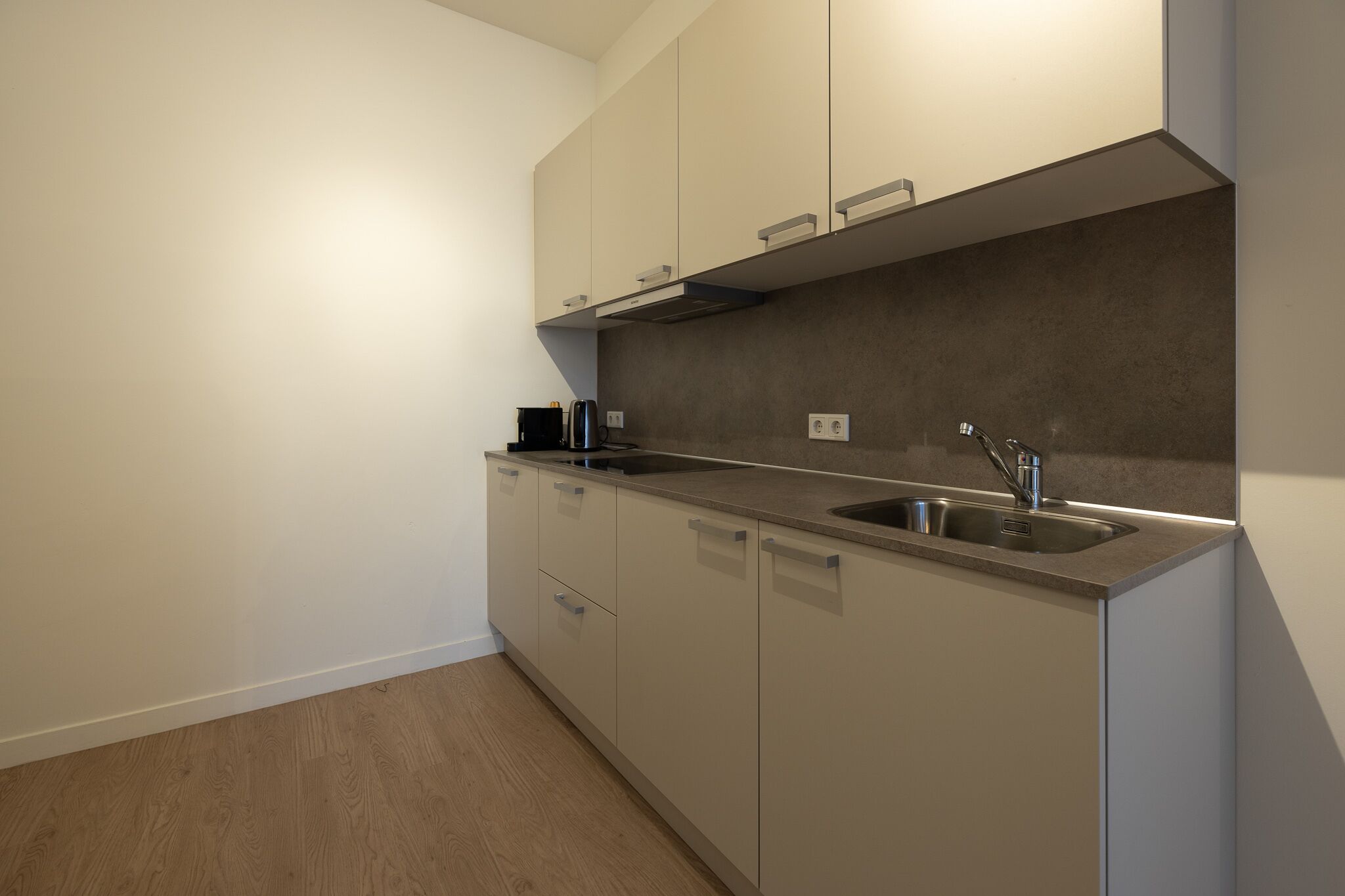 A modern kitchen with a stainless steel sink, a built-in oven, and a microwave.