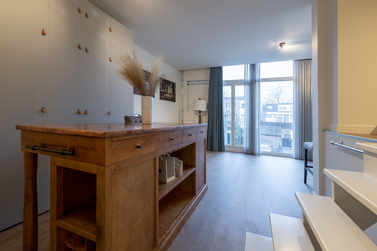 Eine moderne Küche mit Holzausstattung, einer zentralen Kochinsel und Blick auf die Stadt durch große Fenster.