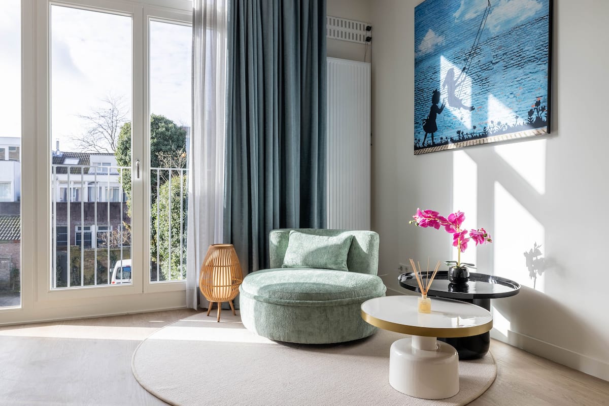 Ein modernes Wohnzimmer mit einem runden, grünen Sofa, einem runden Couchtisch und einem Gemälde an der Wand.