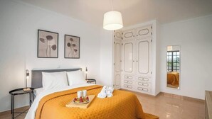 A hotel room with a bed, a bedside table, a nightstand, a wardrobe, and a mirror. - Spacious House | Terrace & Pool by Host Wise (Lagoa)