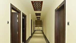 A hotel hallway with a central corridor, wooden doors, and a ceiling with a decorative pattern. - Hotel Rudra Inn  (Bakshi Ka Talab)