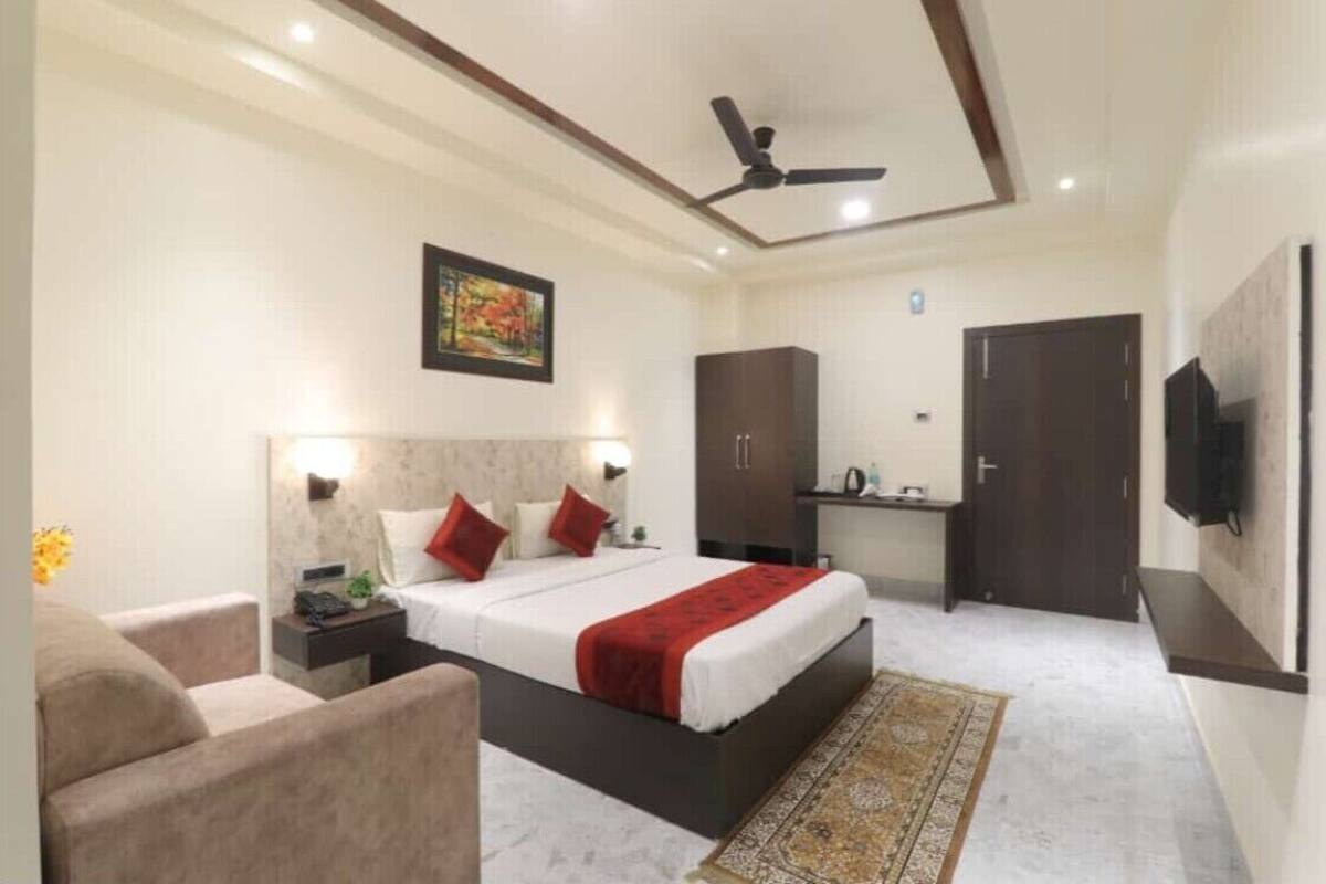 A bedroom with a bed, bedside tables, a desk, a wardrobe, a ceiling fan, and a TV mounted on the wall.