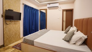 A bedroom with a bed, a flat-screen TV, an air conditioning unit, and a mirror. - HOTEL TOURIST INN BY SAGAR (Siliguri)