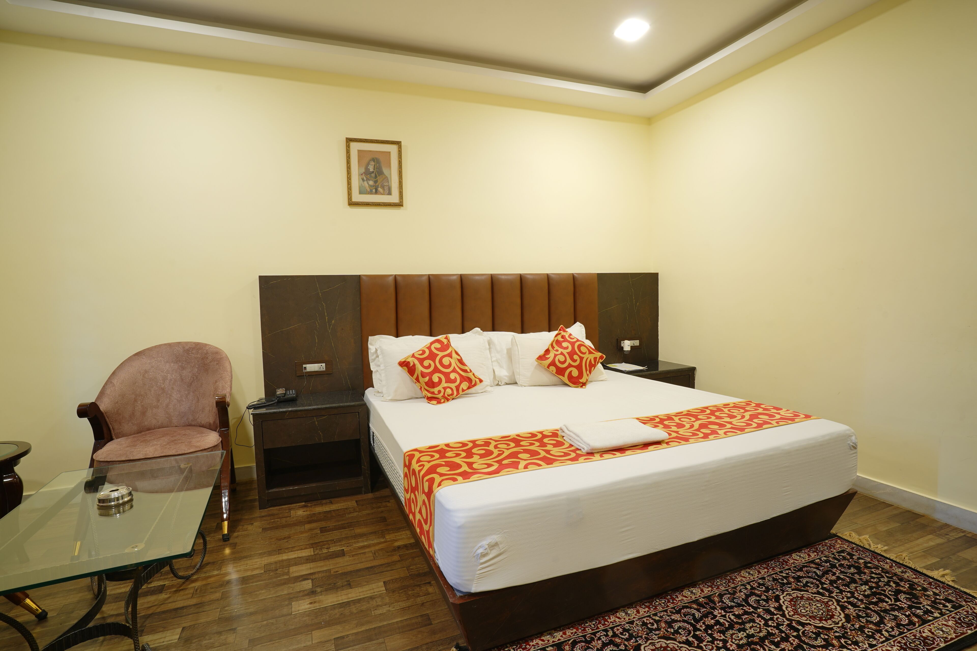 A hotel room with a bed, a chair, a table, and a nightstand.
