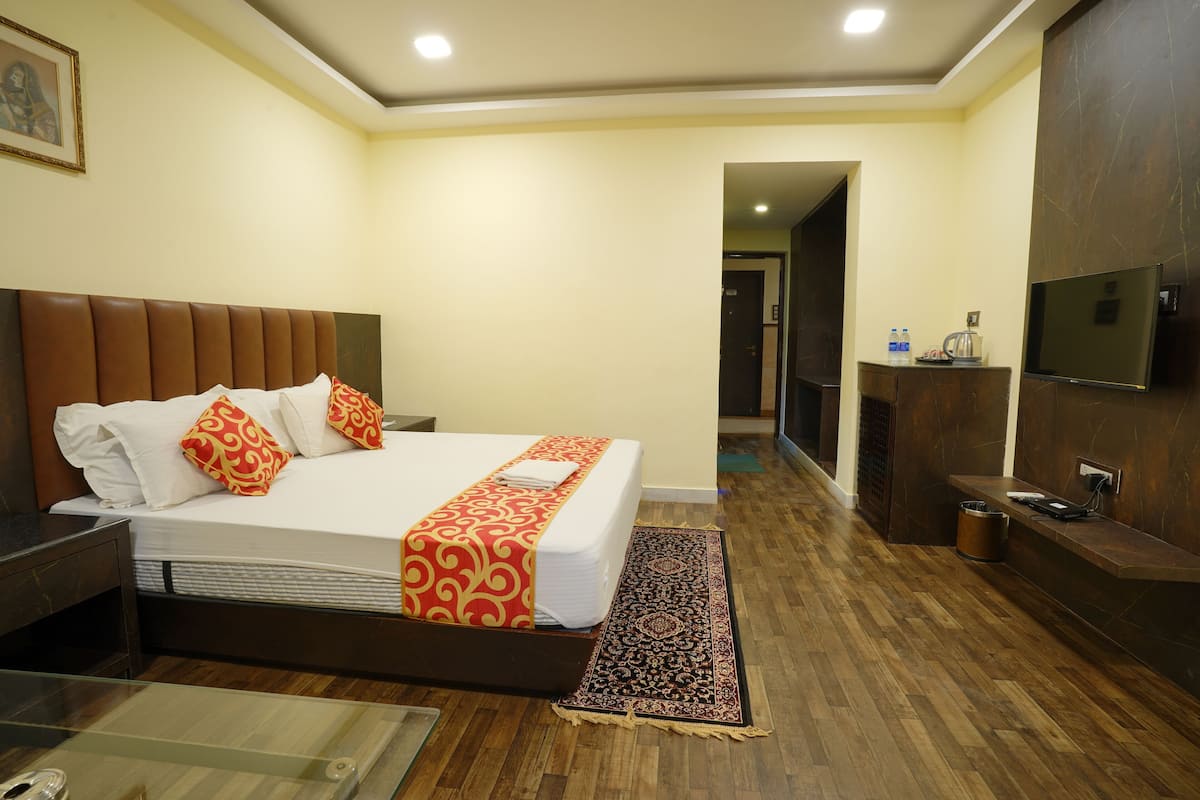 A hotel room with a large bed, a TV, a desk, and a bathroom area.