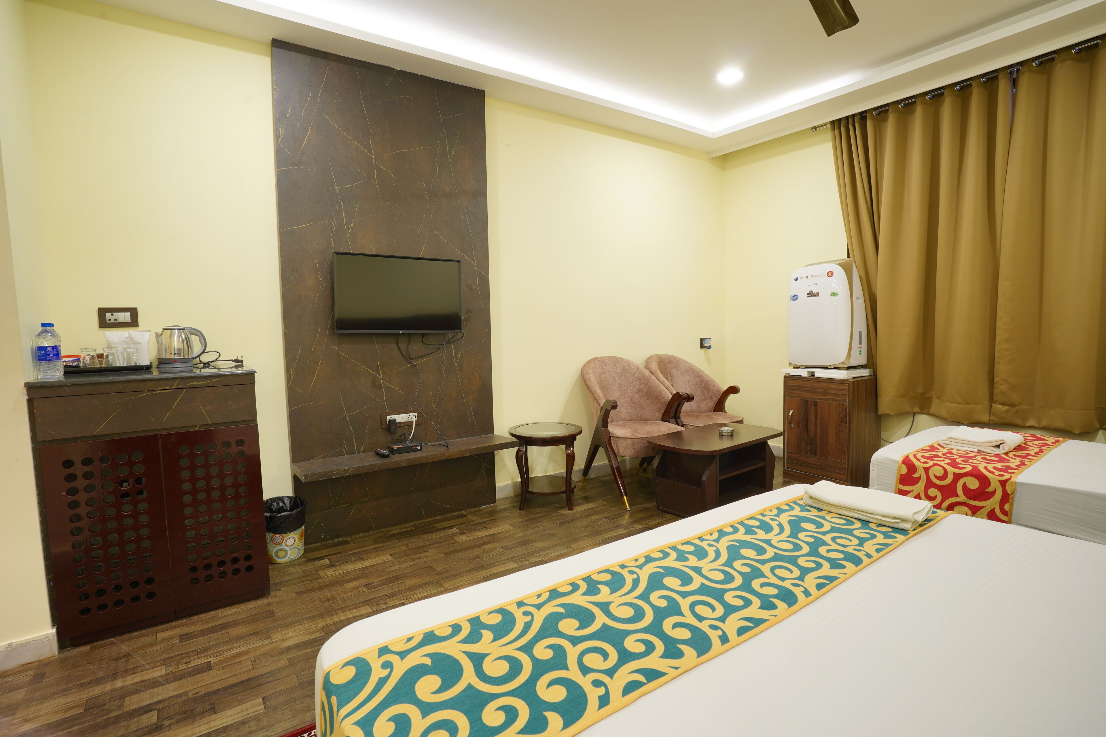 Une chambre d’hôtel comprenant un lit, un téléviseur fixé au mur, une petite table, une chaise, un minibar et une salle de bain.