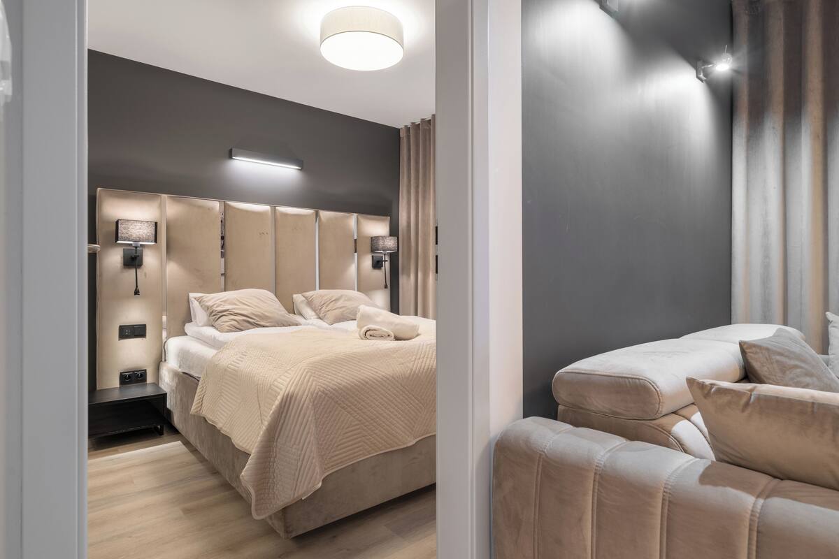Un dormitorio moderno con una cama grande, lámparas de noche y un sofá.