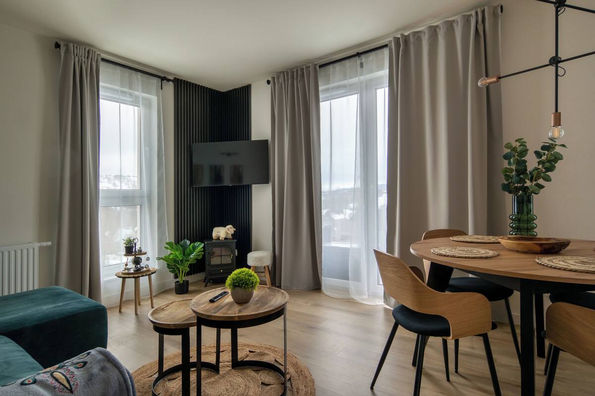Una sala moderna con televisor, mesa de comedor, sillas y un sofá acogedor.