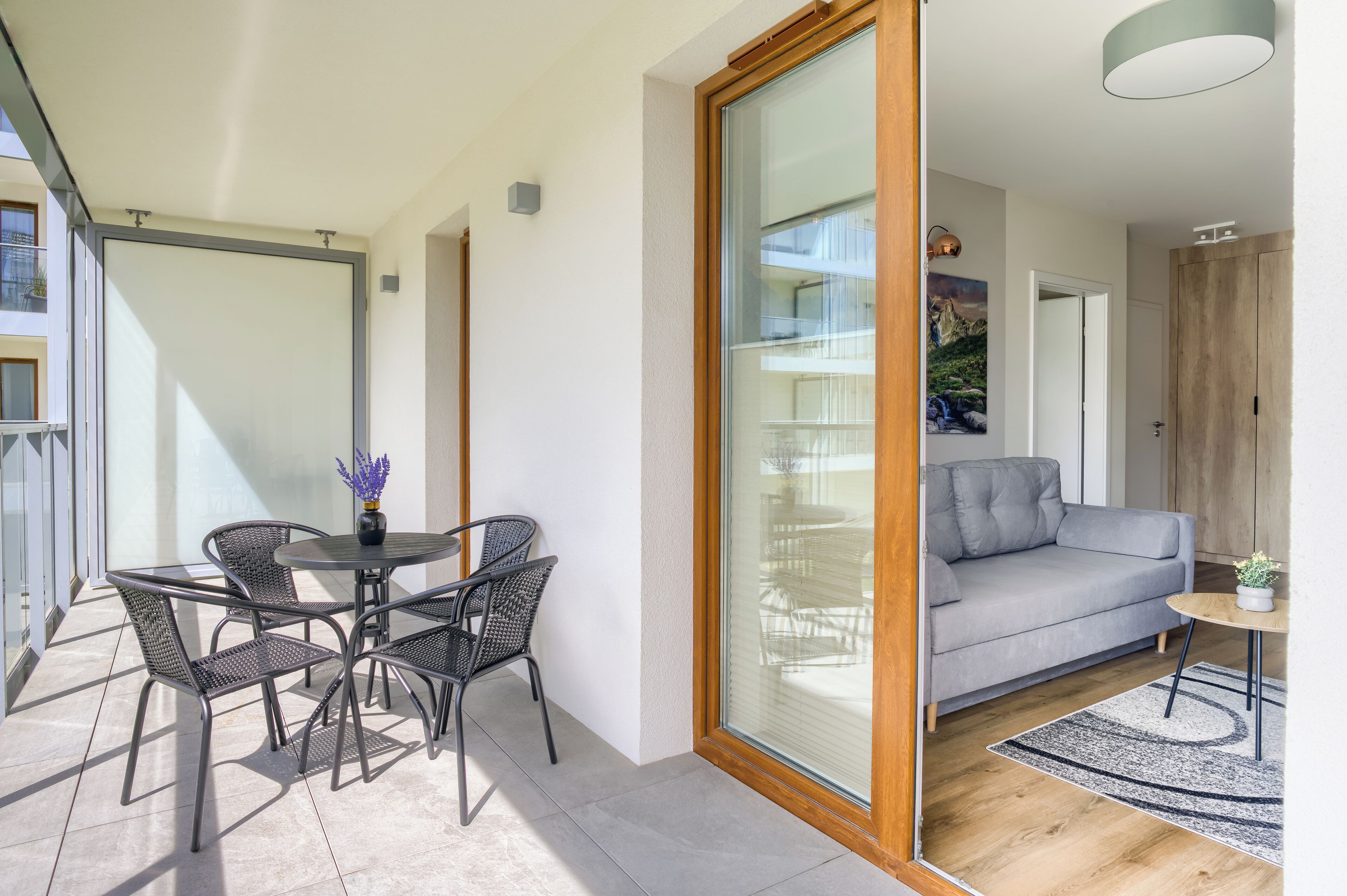 Una sala de estar moderna con un sofá gris, una mesa de comedor redonda con sillas y suelo de madera.