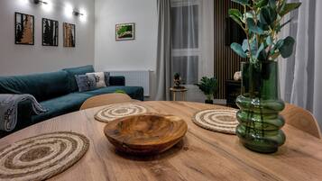 Una sala moderna con una mesa de madera, un jarrón verde y un sofá color turquesa.