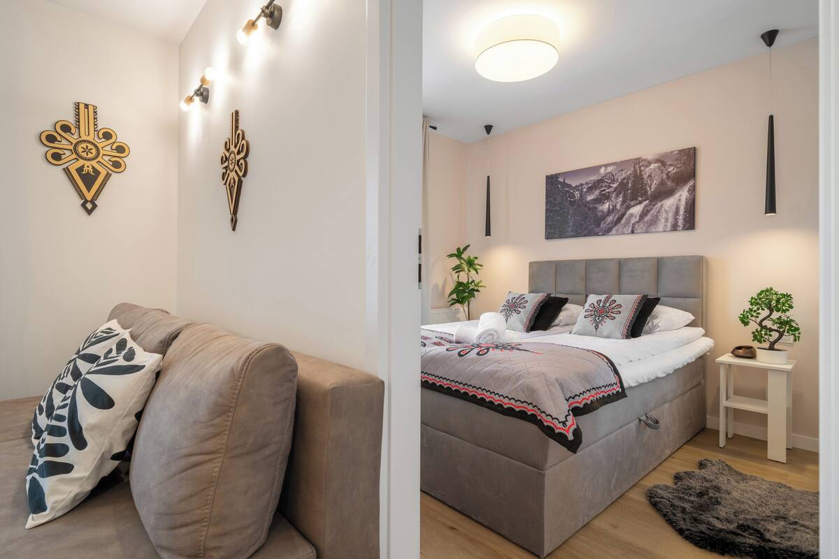 Un dormitorio moderno con cama, sofá, decoración mural y planta en maceta.
