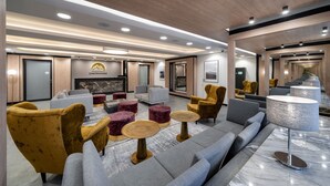 Um hall de hotel moderno com um sofá, poltronas e lareira.